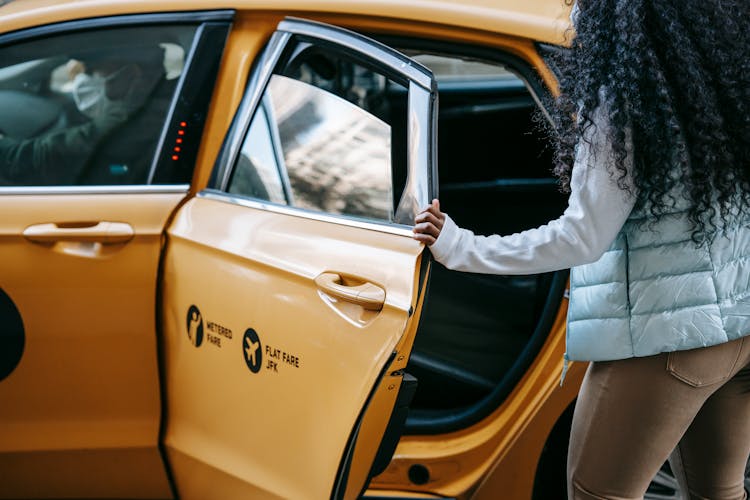 Anonymous African American Woman Getting Into Cab Parked On Street