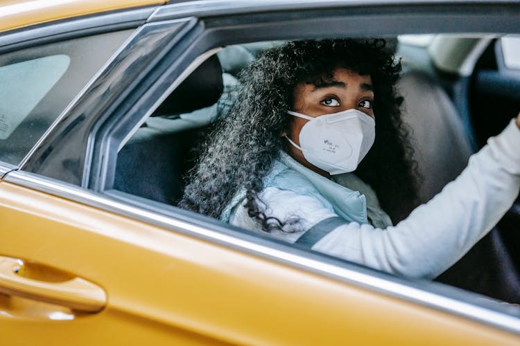 Black Female In Mask In Yellow Car