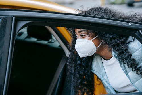 Free Black female in mask getting cab on city street Stock Photo