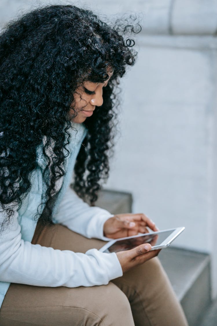 Thoughtful Black Lady Browsing On Tablet On Steps In Street