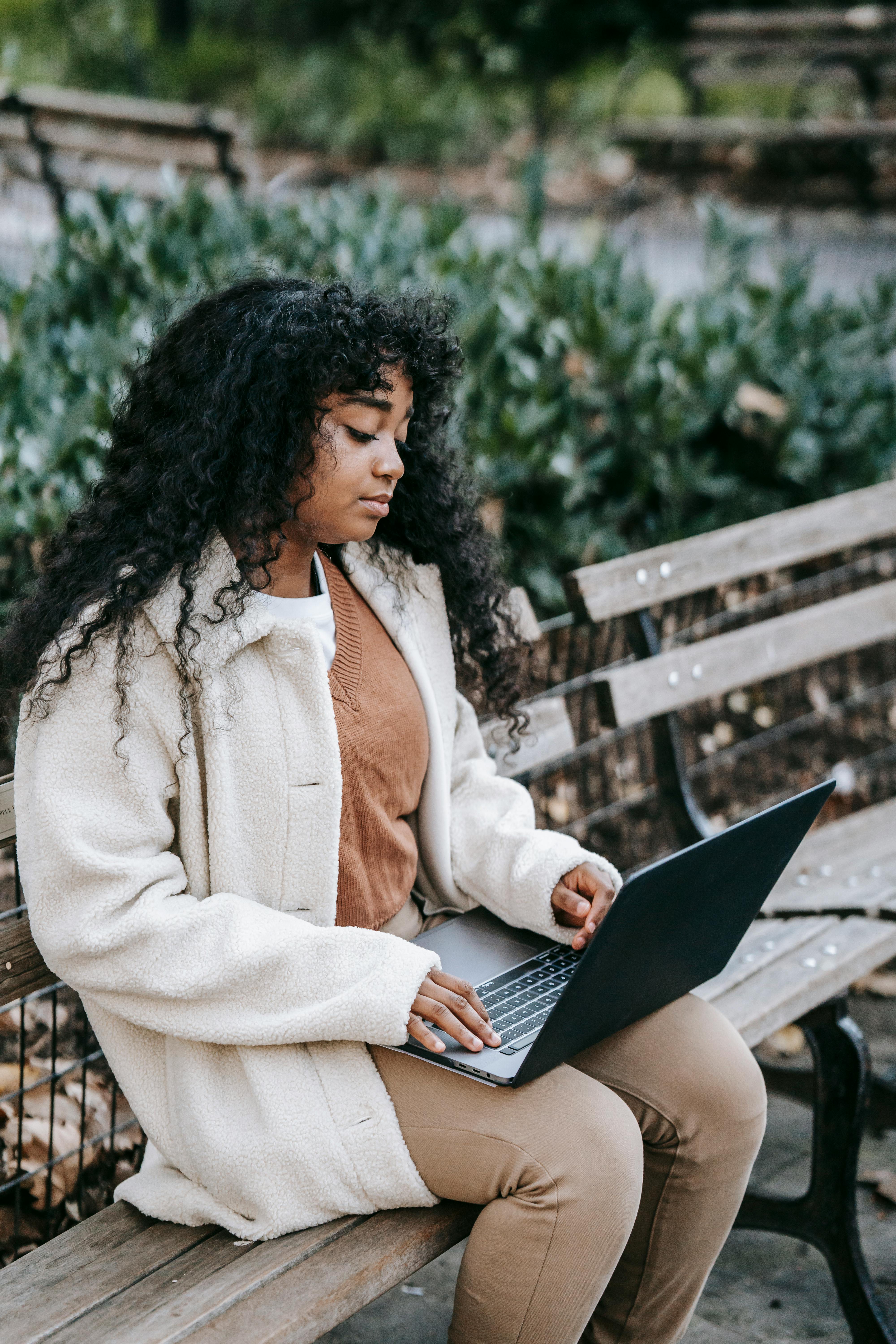 black woman using laptop on park bench