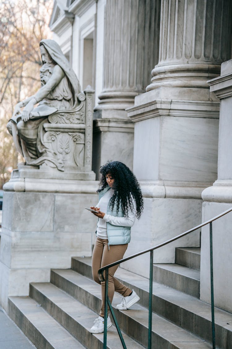 Black Woman Using Tablet And Going Downstairs Old Stone Building