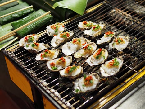 Delicious grilled oysters with spicy chili and herbs on a barbecue grill, perfect for seafood lovers.