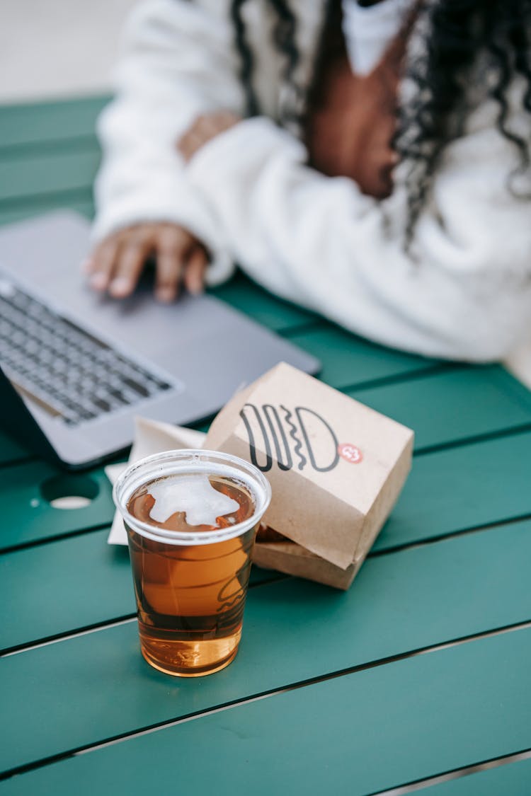 Crop Faceless Black Woman Using Laptop Near Burger And Beer