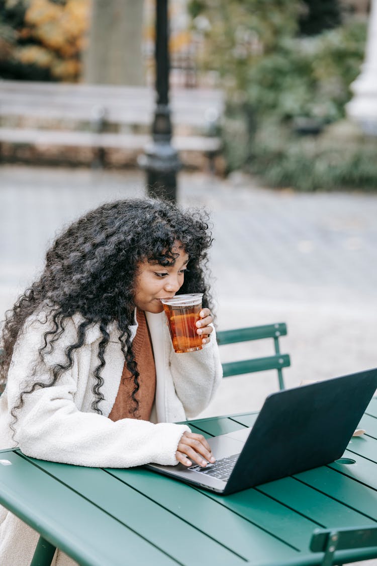 Black Woman Drinking Fresh Beer And Using Laptop In Park