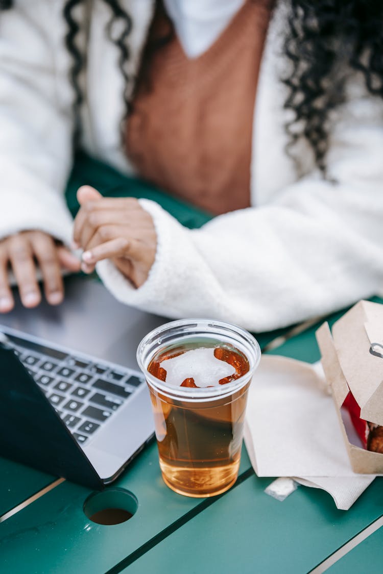 Crop Black Faceless Woman With Glass Of Beer Using Laptop