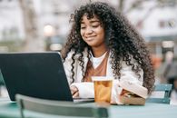Smiling black woman using laptop in city park