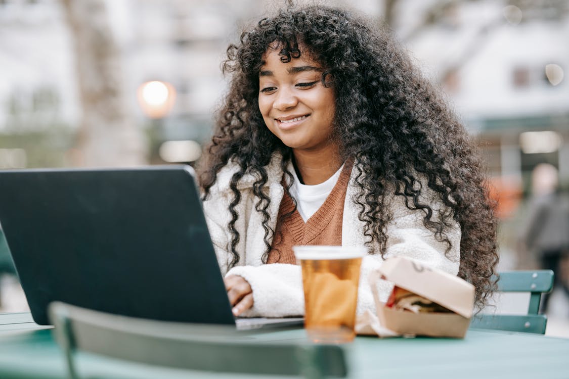 Free Smiling black woman using laptop in city park Stock Photo