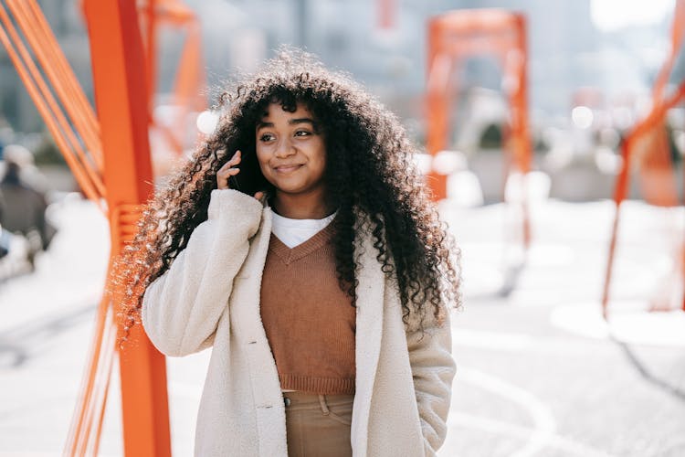 Smiling Black Woman Talking On Smartphone In Sunny Spring Street