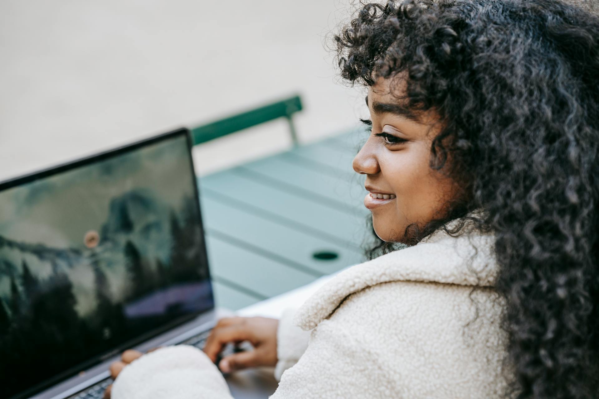 Cheerful black woman browsing laptop in city park