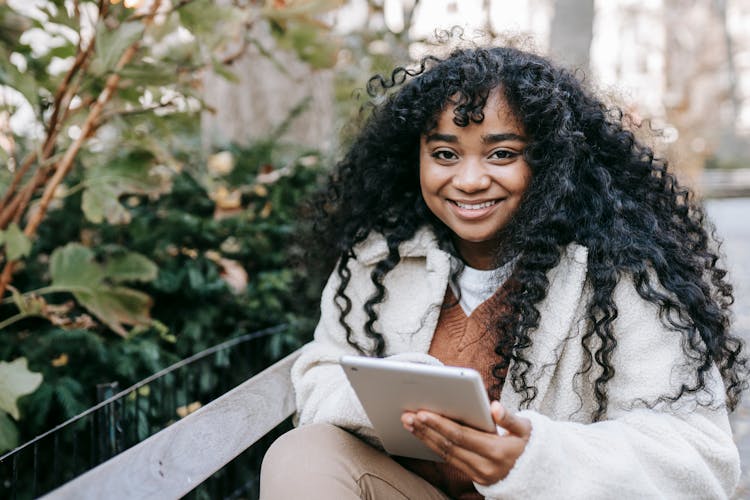 Smiling Black Woman Using Tablet In City Park