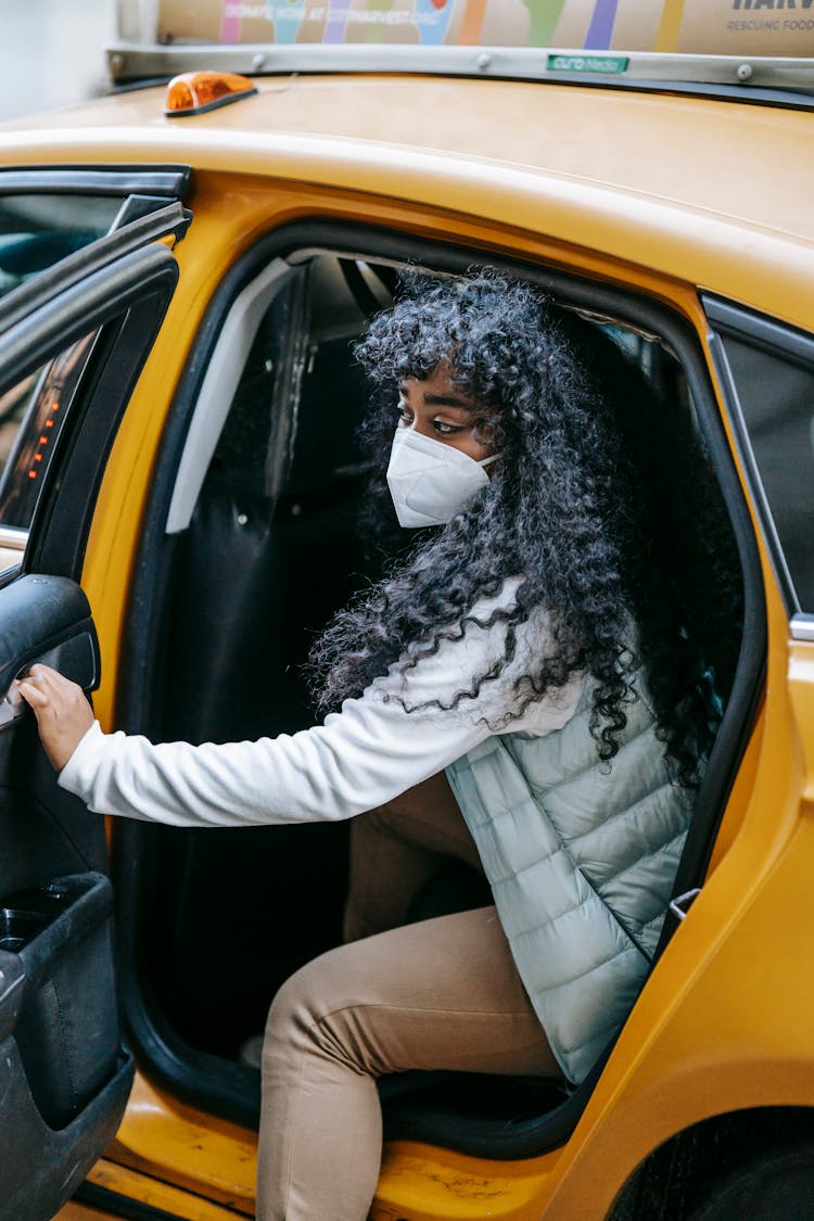 Black Woman In Mask Getting Off Taxi