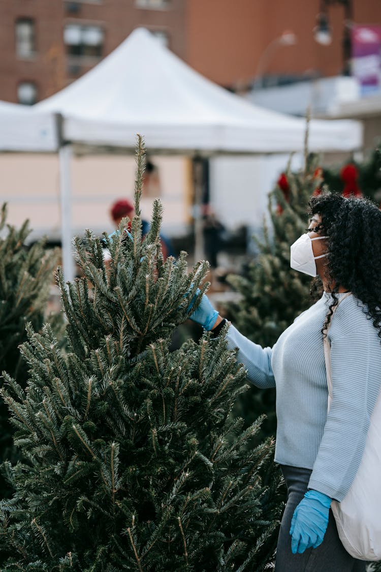 Black Woman In Respirator Checking Fir In Tree Market