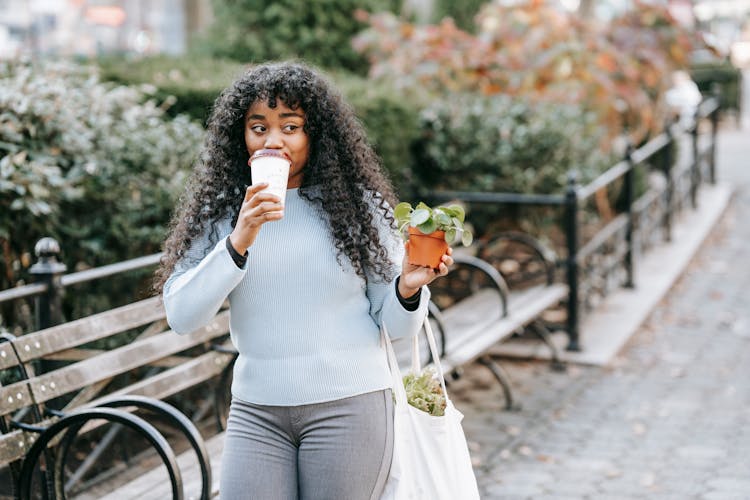 Content Black Woman With Flowerpot Drinking Coffee