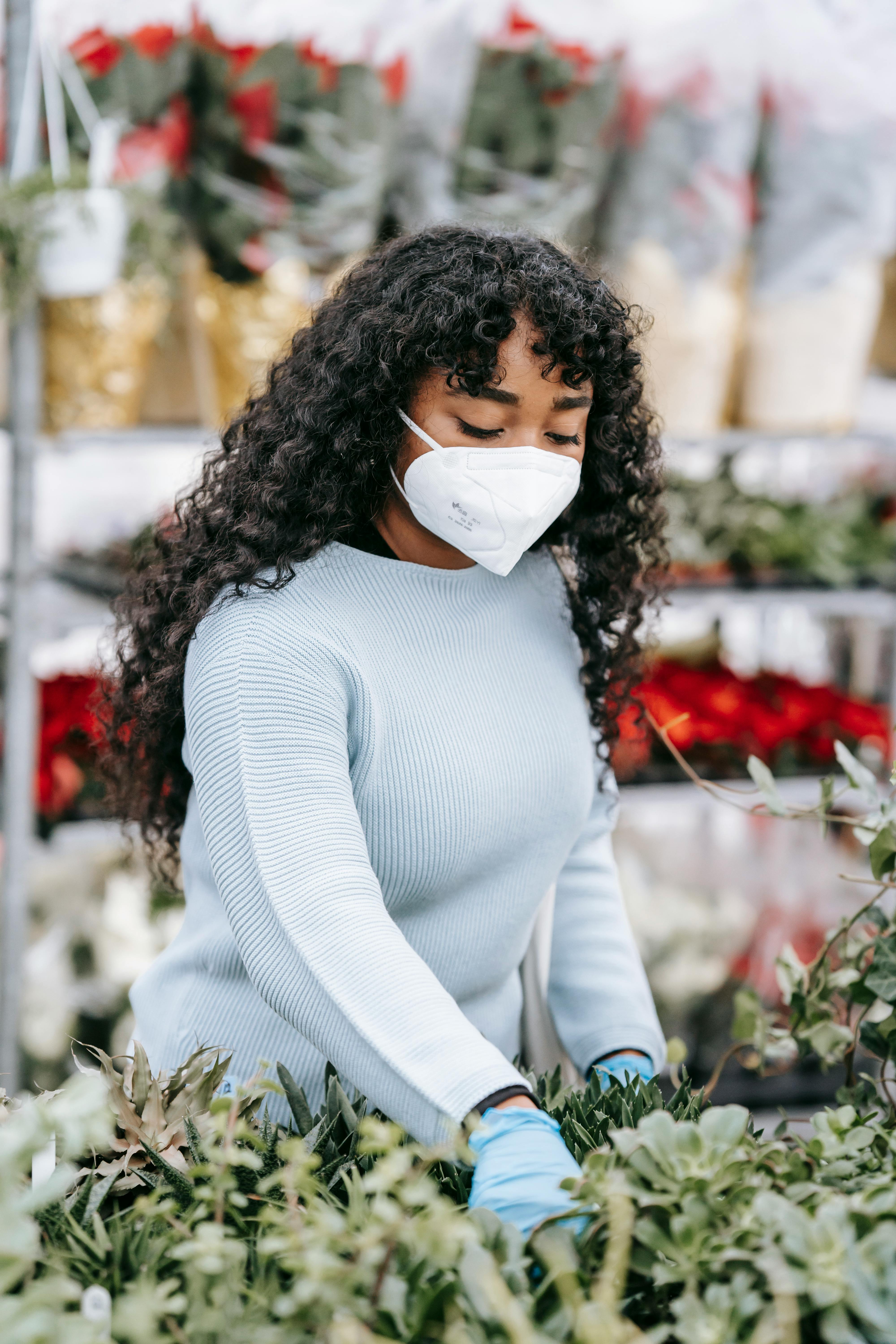black woman in medical mask choosing flowers