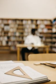 Focused image depicting a drafting triangle on a study desk in a library setting.