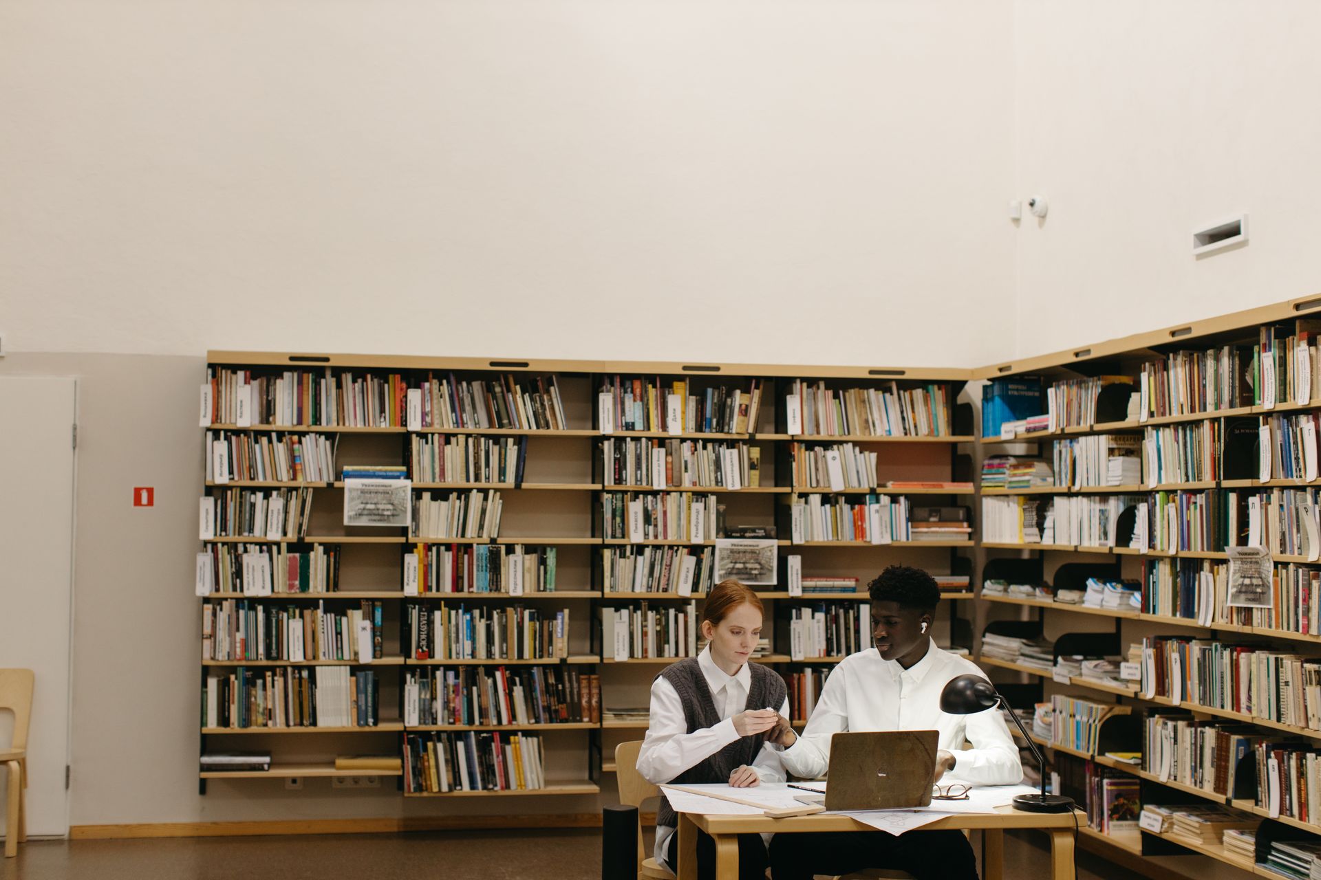 Two diverse students study collaboratively in a library setting.