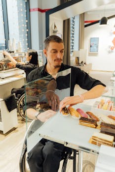 Man in a wheelchair handling pastries in a modern shop setting, showcasing accessibility and inclusivity.