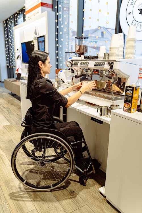 A Woman in a Wheelchair Using an Espresso Machine