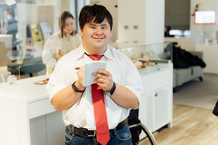 A Cheerful Man Holding A Notepad And A Pen