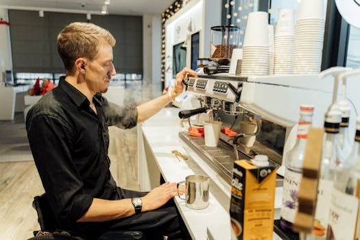 Barista in wheelchair using espresso machine to make coffee in a modern cafe setting.