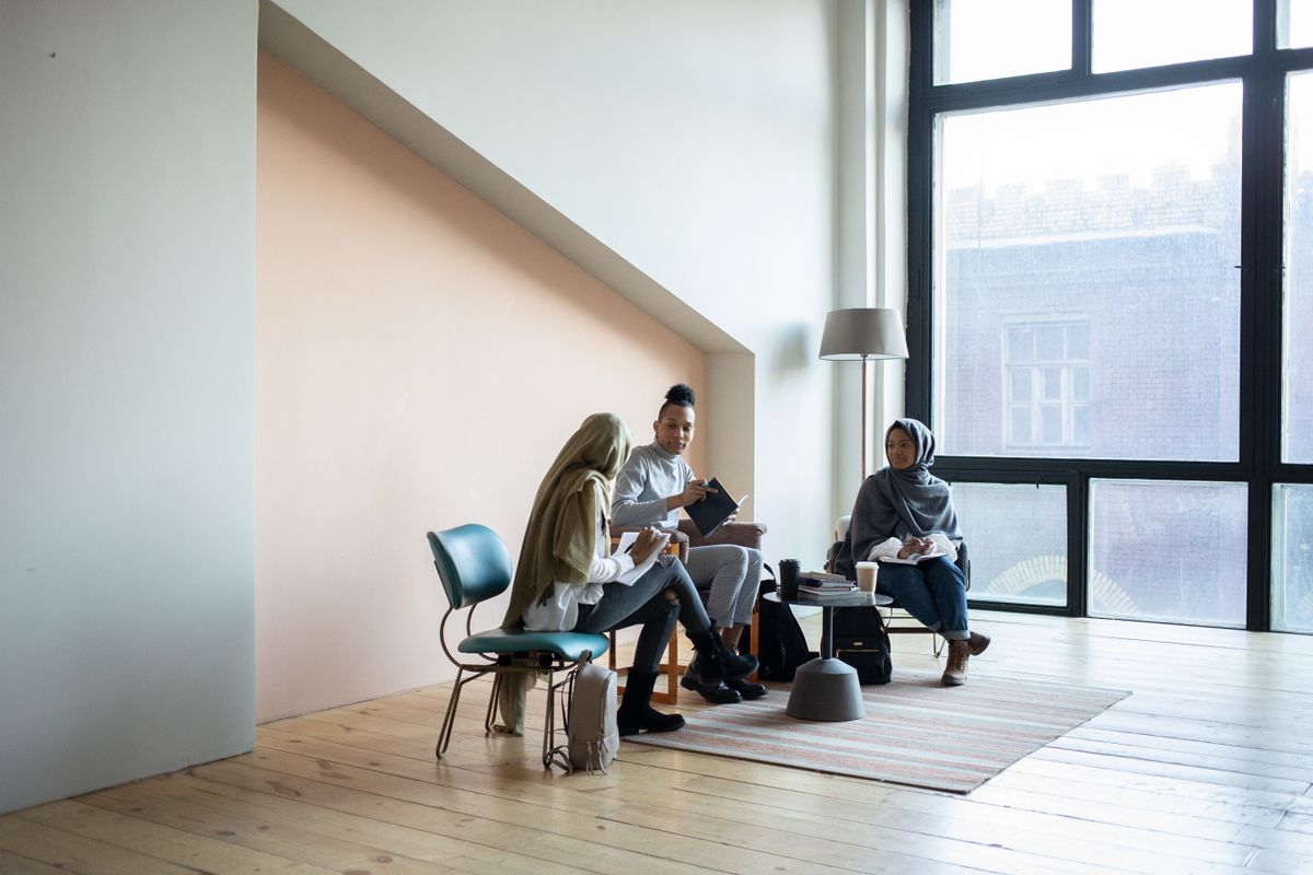 Group of young professional American women collaborating in a modern loft office with brick walls and large windows