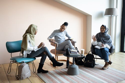 Free Full length positive young multiracial coworkers in casual outfits gathering in light coworking space and discussing business project together Stock Photo