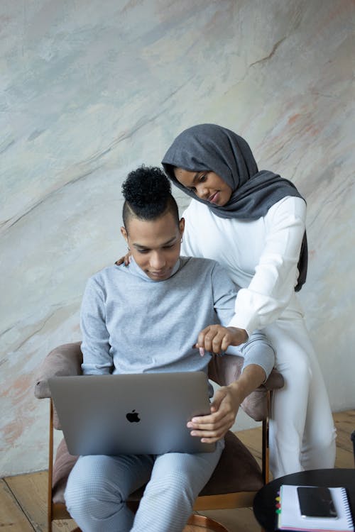 Young ethnic friends browsing laptop in light room