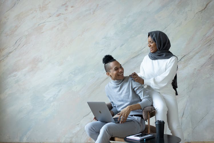 Laughing Ethnic Couple Browsing Laptop On Armchair