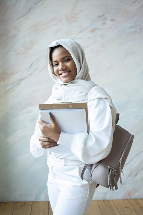 Positive black woman with clipboard and documents