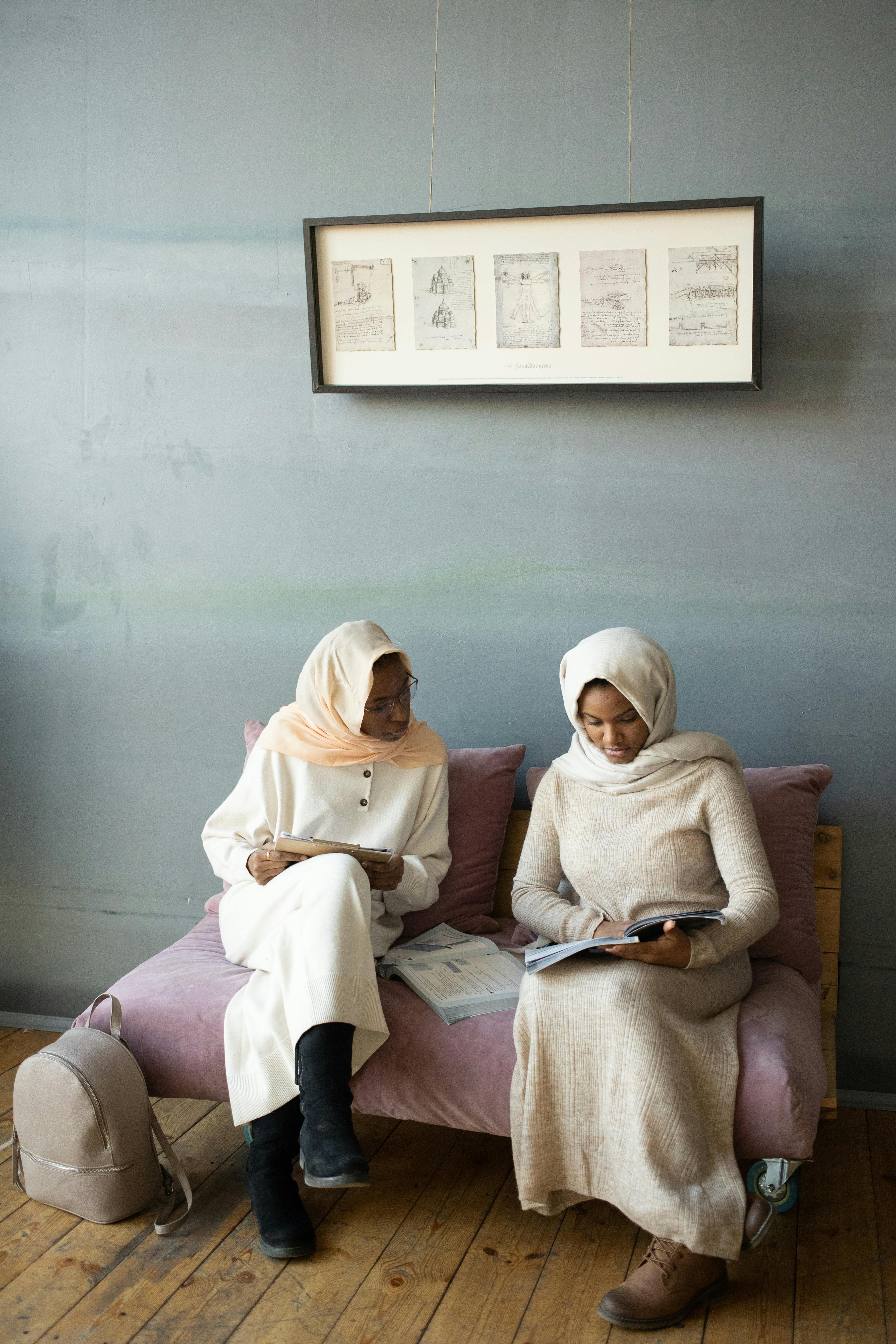 black women reading book together on sofa