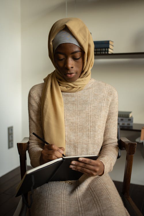 Femme En Hijab Beige Et Chemise à Manches Longues Marron Assis Sur Une Chaise En Bois Marron