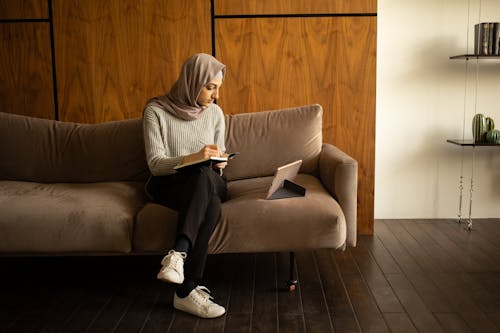 Free Frau Im Weißen Hijab, Der Auf Der Braunen Couch Sitzt Stock Photo