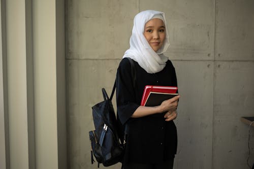 Content Asian woman in hijab with notebooks