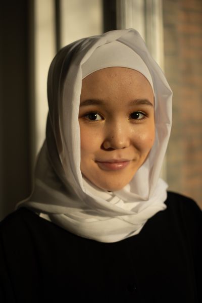 Headshot of cheerful Muslim female in traditional headscarf looking at camera
