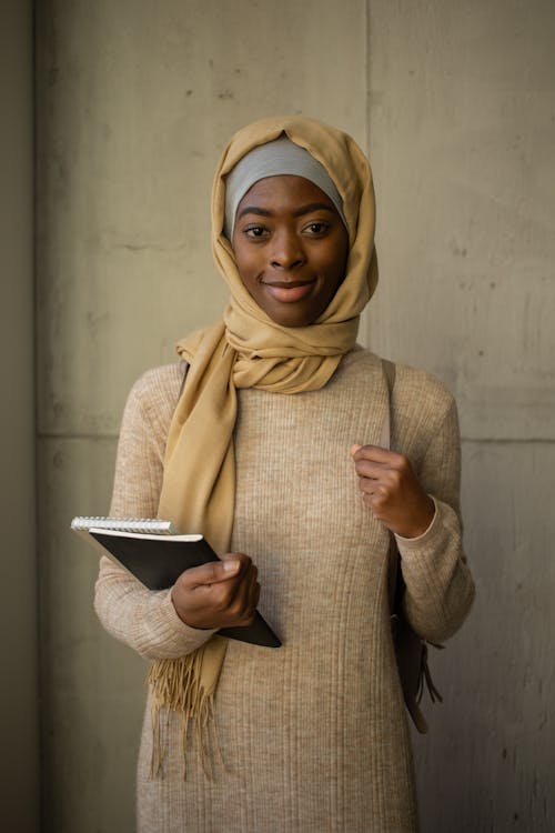 Smiling black woman in hijab with notebooks