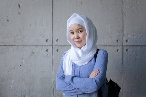 Positive Asian woman in hijab standing in campus of university