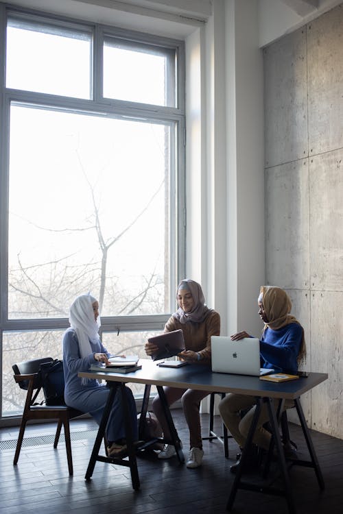 Free Diverse Muslim women with gadgets studying at table Stock Photo