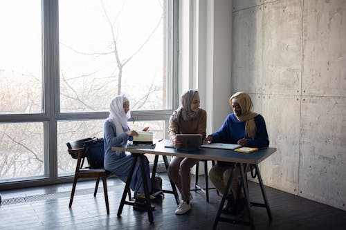 Diverse Muslim businesswomen talking about job at table with tablet