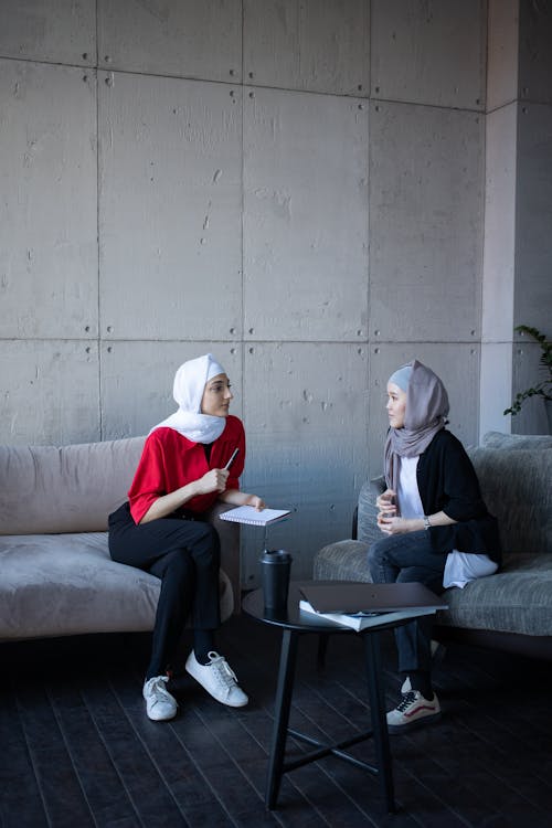 Free Islamic multiethnic women in headscarves discussing plan of job together in comfortable workplace in daytime Stock Photo