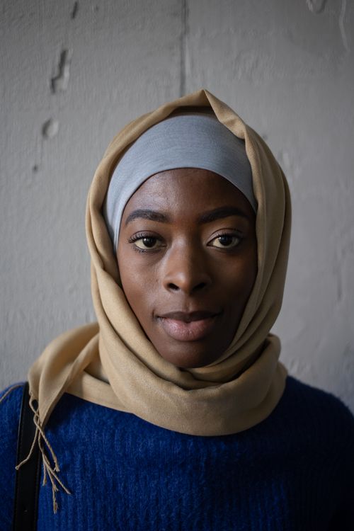 Free Confident black Islamic woman wearing casual clothes and hijab looking at camera near gray shabby wall in light place Stock Photo