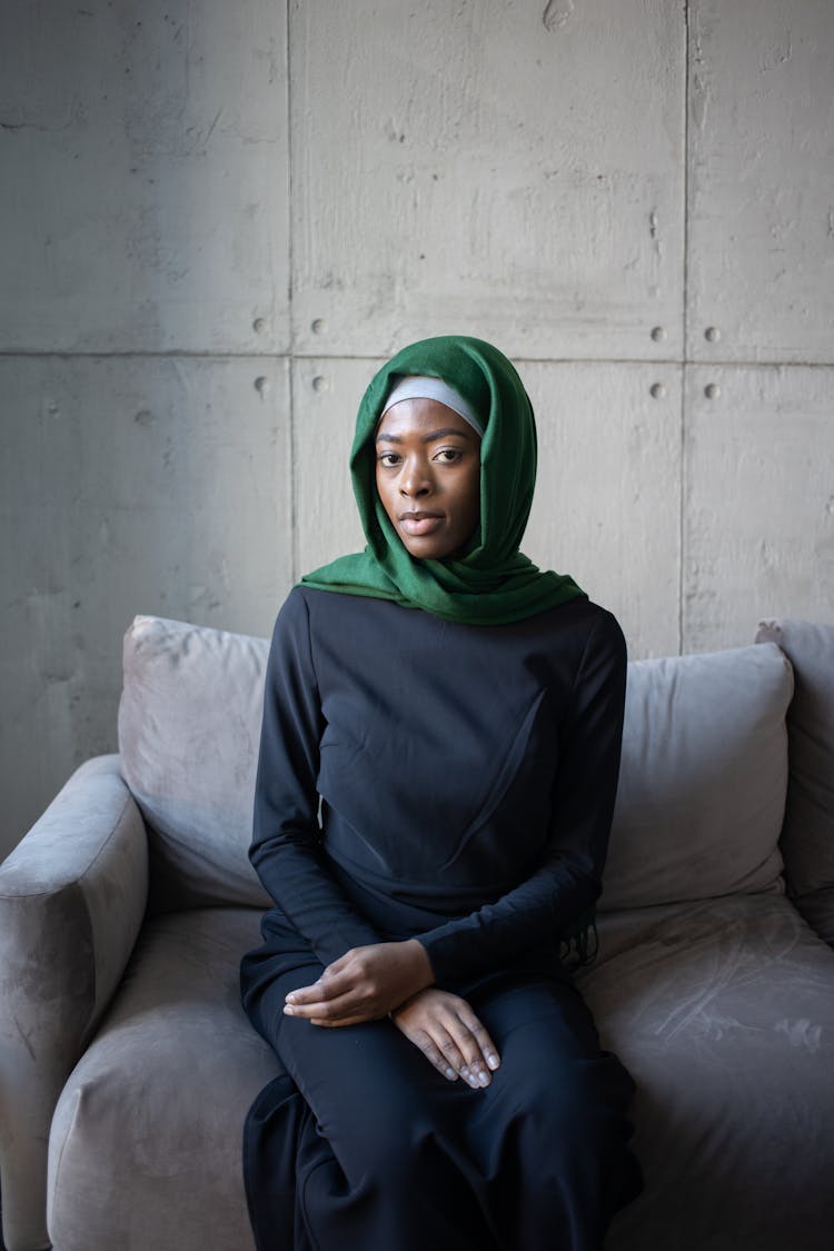 Islamic Black Female In Hijab On Sofa Near Wall