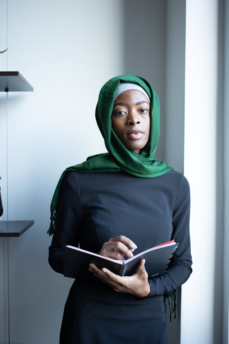 Serious Black Muslim Lady In Hijab With Notebook