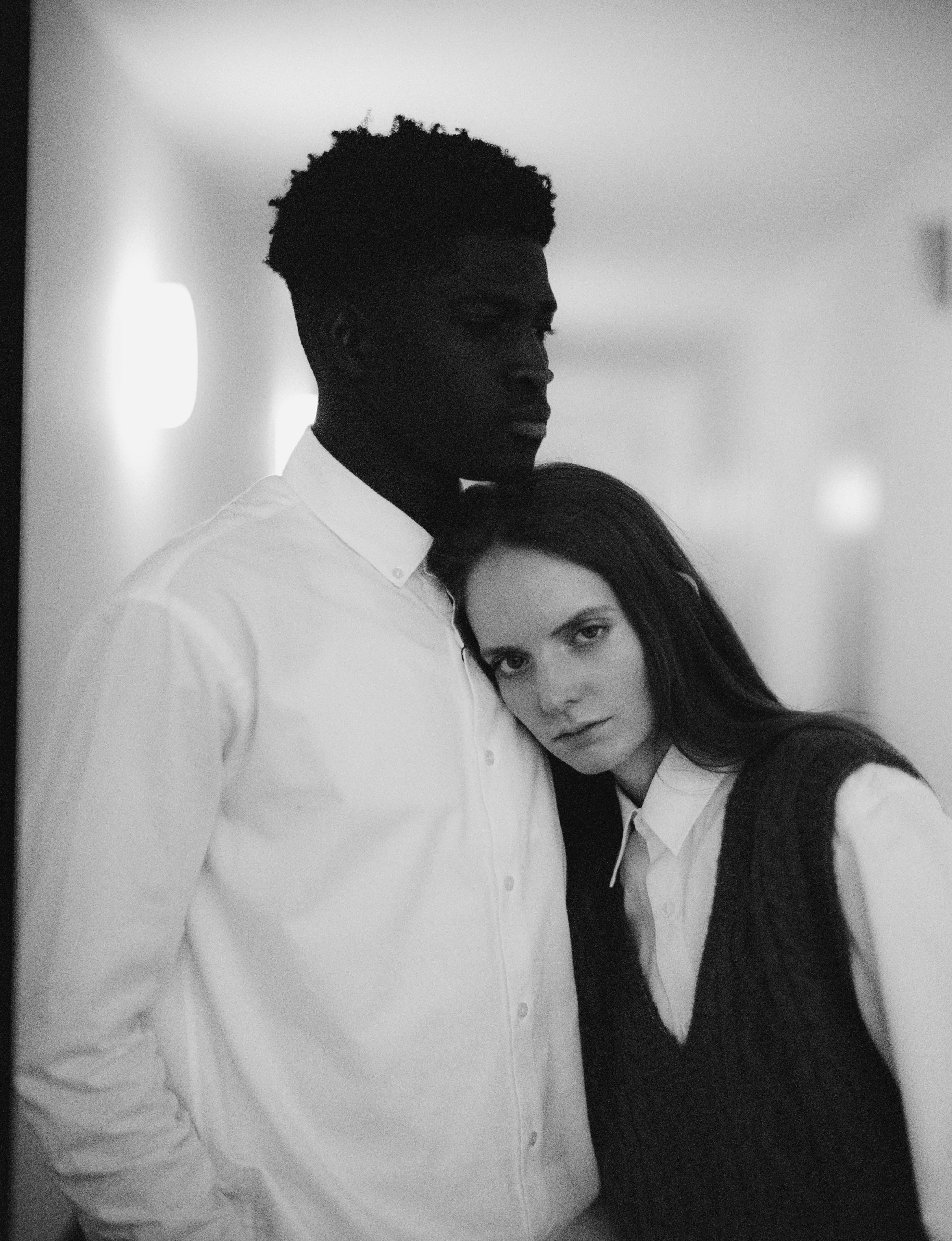 A touching black and white portrait of a multiracial couple in a serene moment indoors.