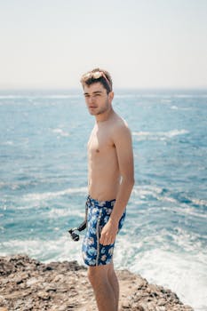 Shirtless young man in shorts enjoying the sunny coast of Naxos, Greece.