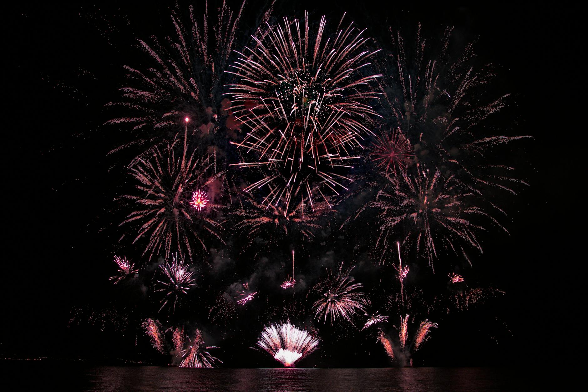 A vibrant fireworks show lighting up the night sky over water, perfect for celebrations.