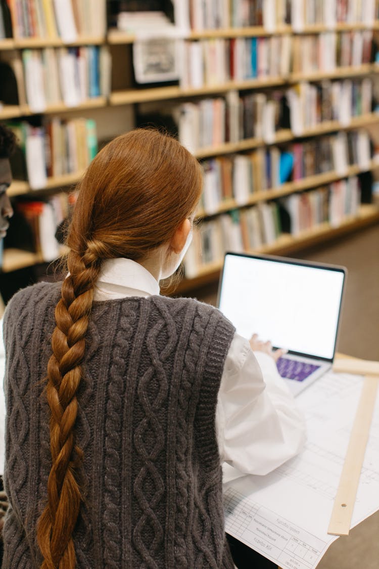 A Back View Of A Woman Using Her Laptop