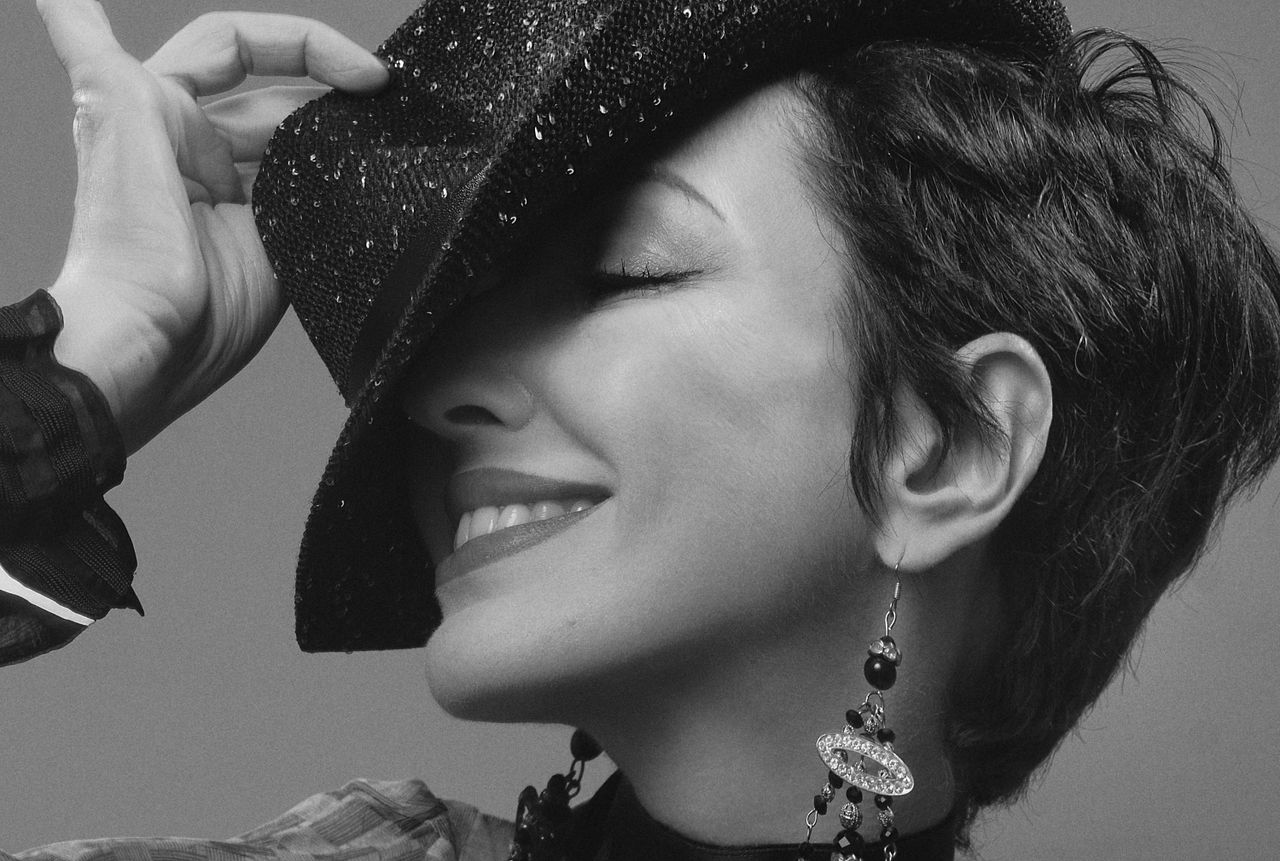 chic monochrome portrait of a woman smiling while tipping her fedora h