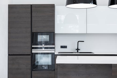 Interior detail of modern kitchen with minimalist furniture contemporary appliances decorated with lamps hanging over counter