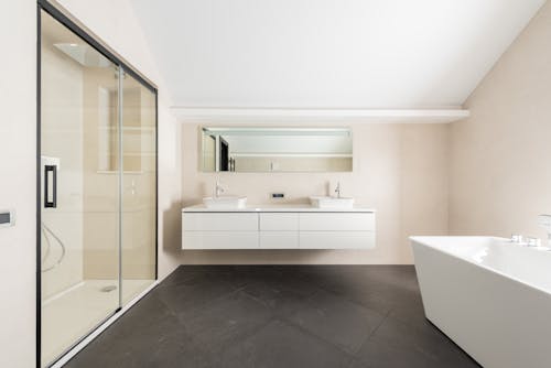 Interior of spacious modern bathroom with shower cabin bathtub and minimalist furniture in contemporary apartment